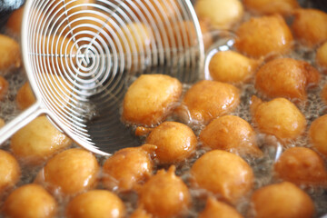 Fritule - Croatian mini doughnuts. Oil frying process. Selective focus