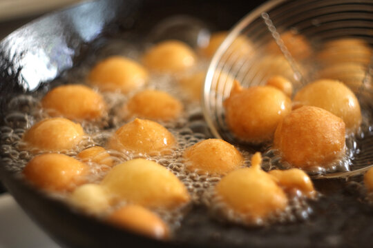 Fritule - Croatian mini doughnuts. Oil frying process. Selective focus