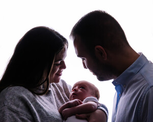 Parents embracing newborn baby creating family silhouette