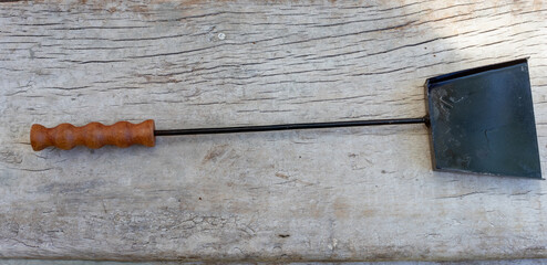 Barbecue shovel on a rustic wooden board, ready for outdoor cooking. Camping and grilling...