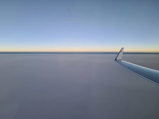 view out of an airplane on the tip of the wing over cloudy sky short after sunset