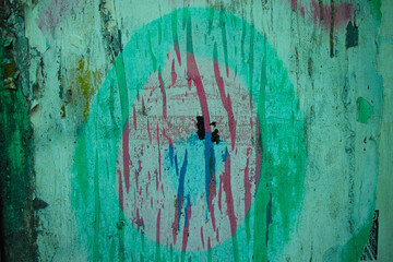 Wall featuring a circular street art symbol in teal, red and blue on a distressed green background