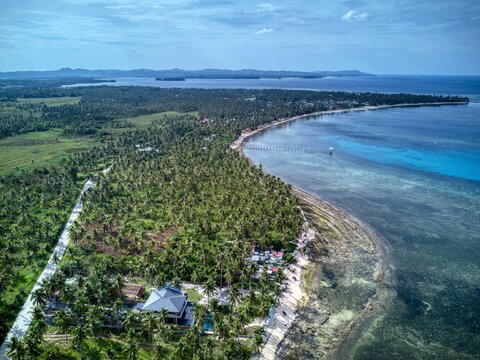 Aerial of wooden pier and outrigger boats over shallow reef - Powered by Adobe