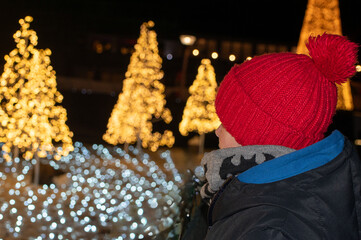 Boy in Red Pom-Pom Hat Looking at Christmas Lights