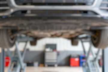Bottom view of a car on a car lift at mechanic's shop.. blurry image 