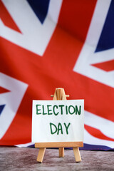 Paper note with words ELECTION DAY on National symbol of Great Britain. British wave the UK silky flag background. Concept of election political participation campaign and civic engagement 