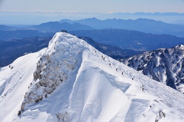 雪の谷川岳に登る登山者たち