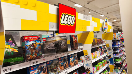 Naklejka premium Potsdam, Germany - October 21, 2025: LEGO display in a retail store showcasing various sets including Ninjago and City, highlighting vibrant colors and playful atmosphere for children