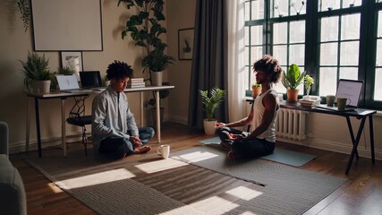 Young multiethnic couple meditating together in their home office, taking a break from work to practice mindfulness and improve mental well being