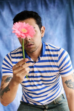 Chico joven latino sosteniendo flor sobre su rostro en sesi&oacute;n fotogr&aacute;fica 