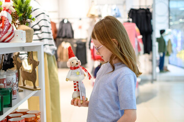A girl in a store among Christmas decorations. Preparing for the New Year and Christmas. Buying decorations and gifts.