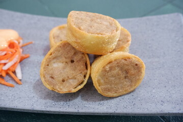 Crispy chicken egg rolls sliced and displayed on a speckled plate, perfect for appetizer, catering, or food content.