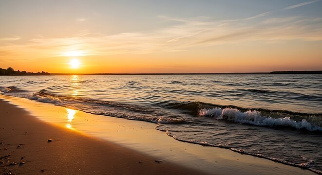 Golden sunset over a calm ocean with gentle waves lapping on the sandy beach shore