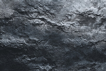 Close up view of a rough dark textured surface with highlights and shadows