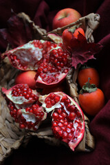 Ripe pink pomegranate in a wicker basket. Juicy pomegranates on a dark background. Fresh fruits. Picking pomegranates in the garden. Vitamins. Food. Close-up. Pomegranate seeds. Sweet pomegranates