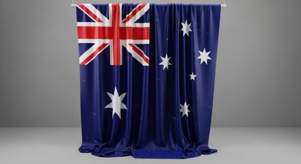 Hanging australian flag with union jack and commonwealth star on a gray studio background.