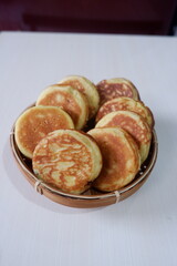 Authentic kue kamir, a beloved snack from Pemalang, Indonesia, displayed in a traditional bamboo basket. These soft, round cakes are known for their fragrant aroma and sweet, comforting flavor. 