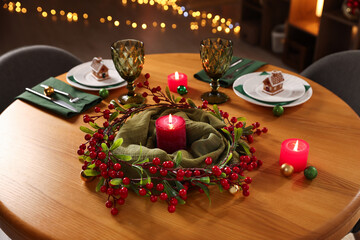 Christmas table setting with plates, glasses and burning candles in festive decorated room, closeup