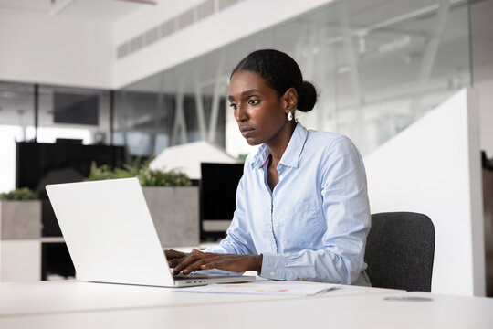Serious African American business project manager woman typing on laptop
