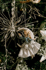 Detailed decorative fairy ornament hanging on a beautifully adorned Christmas tree surrounded by sparkling snowflakes