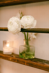 White flowers in a glass vase with candles creating a cozy atmosphere in a rustic setting