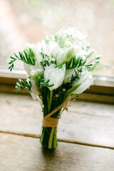 Beautiful white flower bouquet arranged with greenery on a wooden table by a window during daylight