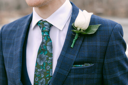Elegant man in suit with floral details at a formal event outdoors on a bright day - Powered by Adobe