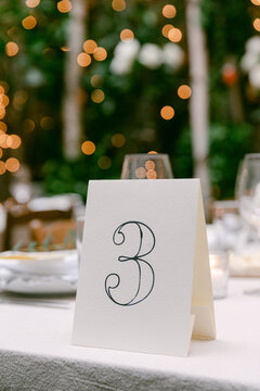 Elegant table number three set against a beautiful bokeh background at an outdoor event