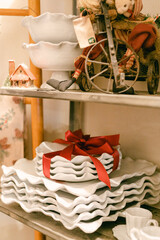 Stacked white serving dishes with red ribbon in a cozy vintage decor shop during the holiday season