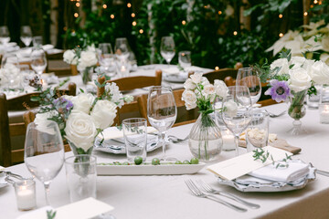 Elegant outdoor dining setup with flowers and candles in a cozy garden at dusk