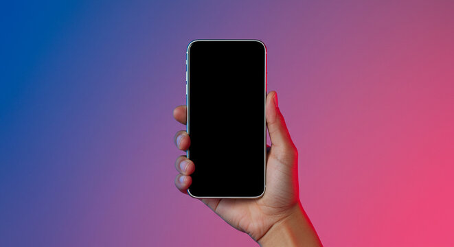 Hand holding modern smartphone with blank screen on vibrant gradient background