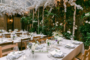 Elegant dining setup with floral decorations and soft lighting in a cozy indoor garden space
