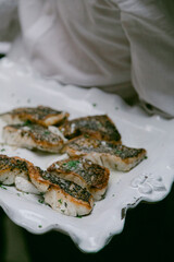 Freshly grilled fish served on a decorative platter at an outdoor gathering in the afternoon light