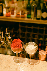 Refreshing cocktails featuring red and white roses on a stylish bar counter with an array of liquor bottles behind