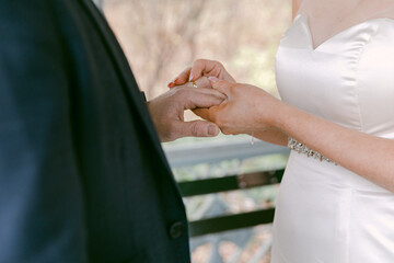 Couple exchanging wedding rings in a serene outdoor setting during a sunny day