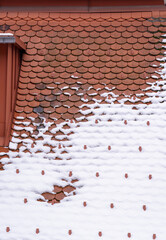 Some snow on a red tile roof