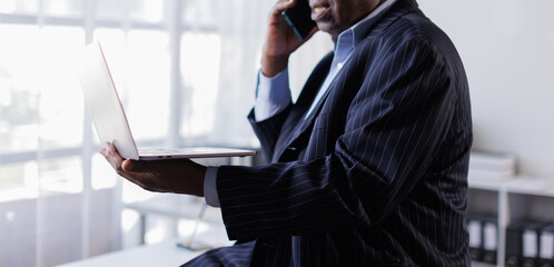 Handsome senior man in business suit working on his laptop in office room.
