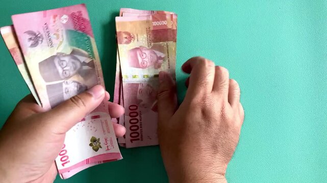 hands counting indonesian rupiah banknotes