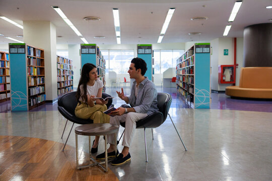 Two university students reading in a cozy library setting, showcasing learning, focus, and collaboration for education and study-themed visuals.
