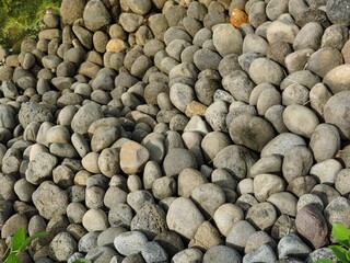 Natural background texture featuring a dense pile of smooth, rounded river stones and pebbles. Ideal for hardscape design or geological abstract use