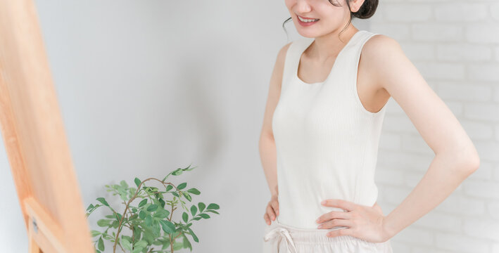 Smiling Asian woman checking her figure and style in the mirror
