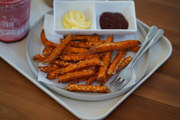 Delicious sweet potato fries served with creamy dipping sauces in a modern restaurant setting, perfect for food photography and culinary inspiration