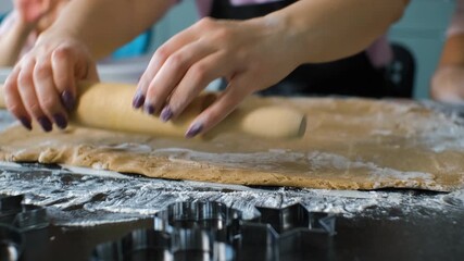Close-up of a mother and rolling ginger cookie dough on a floured surface while her daughters watching, focusing on the tactile process of homemade baking and warm family interaction concept - Powered by Adobe