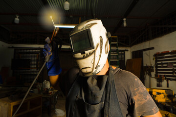 Fototapeta premium Welder threatening cameraman with welding torch. Welding professional showing a welding torch in the workshop