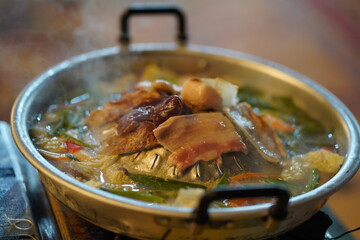 Sizzling Hot Pot with Fresh Ingredients and Delicate Cuts of Meat Steaming on a Table Ready for Enjoyment and Sharing with Family and Friends