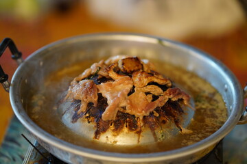 Delicious sizzling meat dish cooking on a metal grill, steam rising from the golden brown surface, showcasing a vibrant culinary experience of grilling.