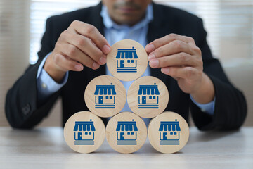 Businessman's hand chooses wooden toy stack with franchise icon for goal to growth is investment planning financial and branch expansion and management bank loans for marketing franchising.