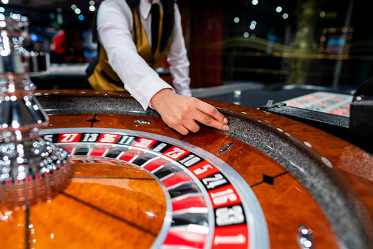 Croupier launching roulette ball on glossy casino wheel, highlighting gambling, betting strategy, risk, luck and entertainment.