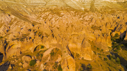 Goreme, Nevsehir, Turkey. Aerial view of unique red rock formations with intricate erosion patterns in Cappadocia desert landscape, evening sunlight.. Aerial View