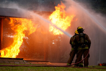 Firefighters battle intense flames during a rescue operation in an outdoor setting